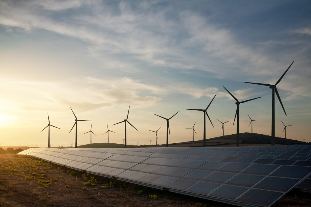 Solar and Wind Farm with Sunset in Background