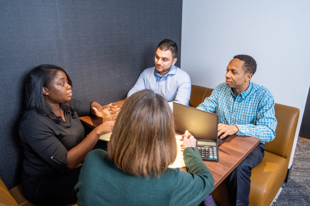 Staff discussing important business around table with laptop and calculator